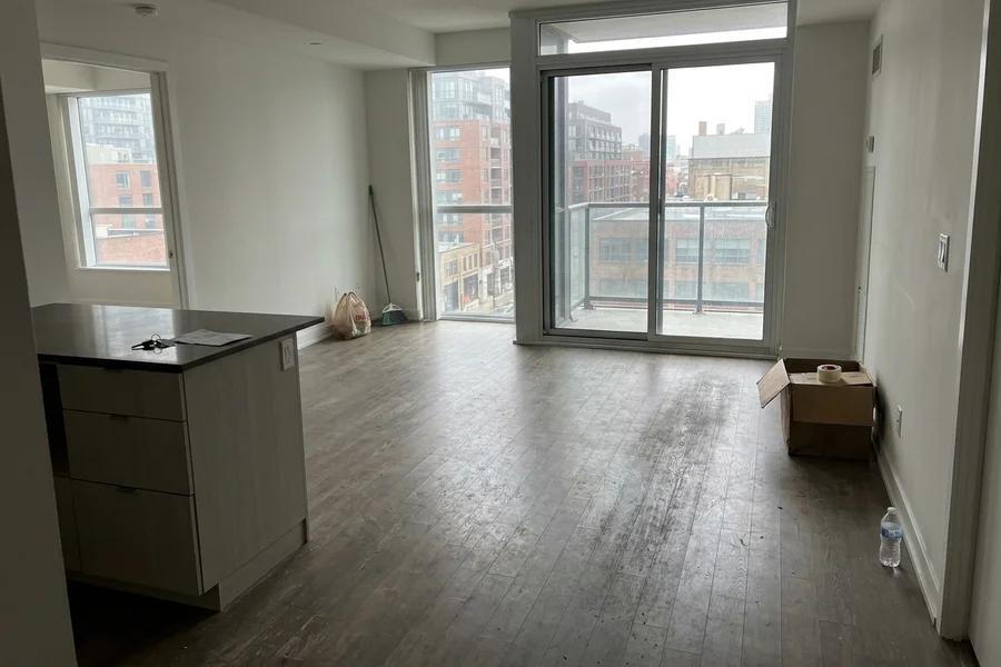 Before engineered hardwood refinishing Toronto: scratched engineered oak in an empty King West condo