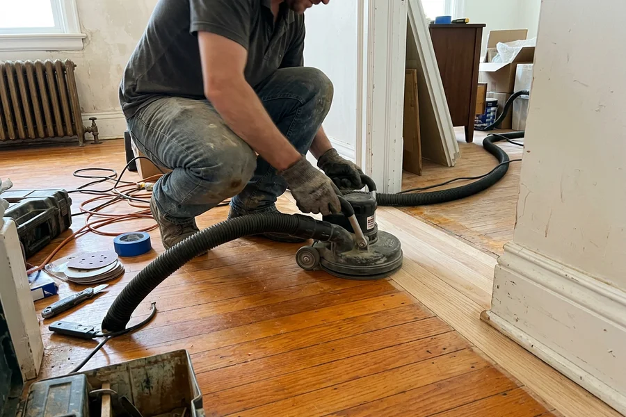 Edger with HEPA hose sanding next to a white baseboard with no dust cloud