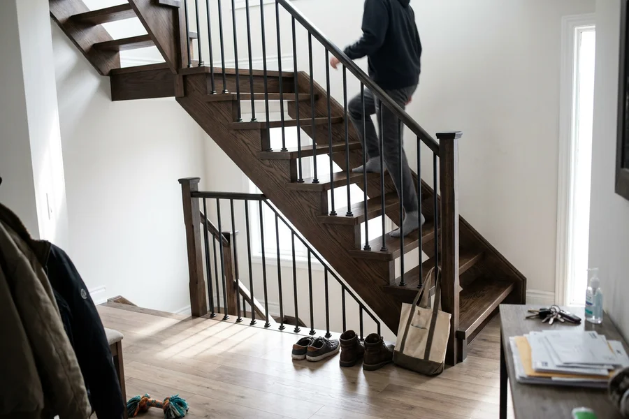 Oak staircase refinished in dark walnut stain with black balusters in North York