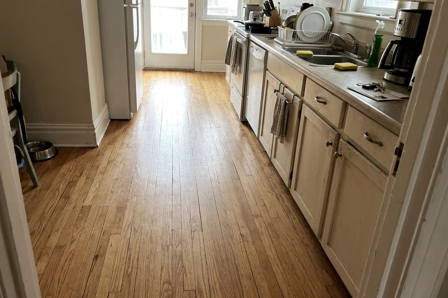 Recoated oak kitchen traffic lane with even satin sheen in Davisville